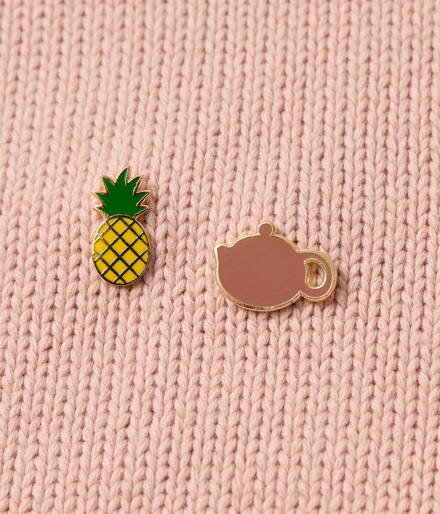 Pineapple and teacup pins on a pink knitted shirt