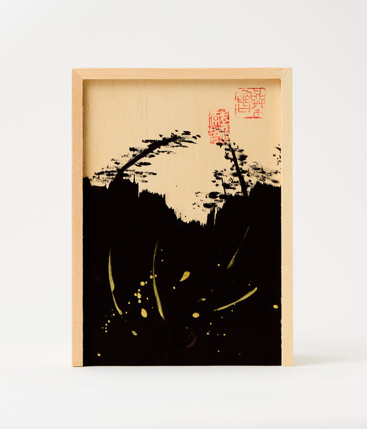 A framed abstract art print featuring a black ink-style landscape silhouette with red seal marks and gold splatter details on a light wood background, set against a clean white backdrop.