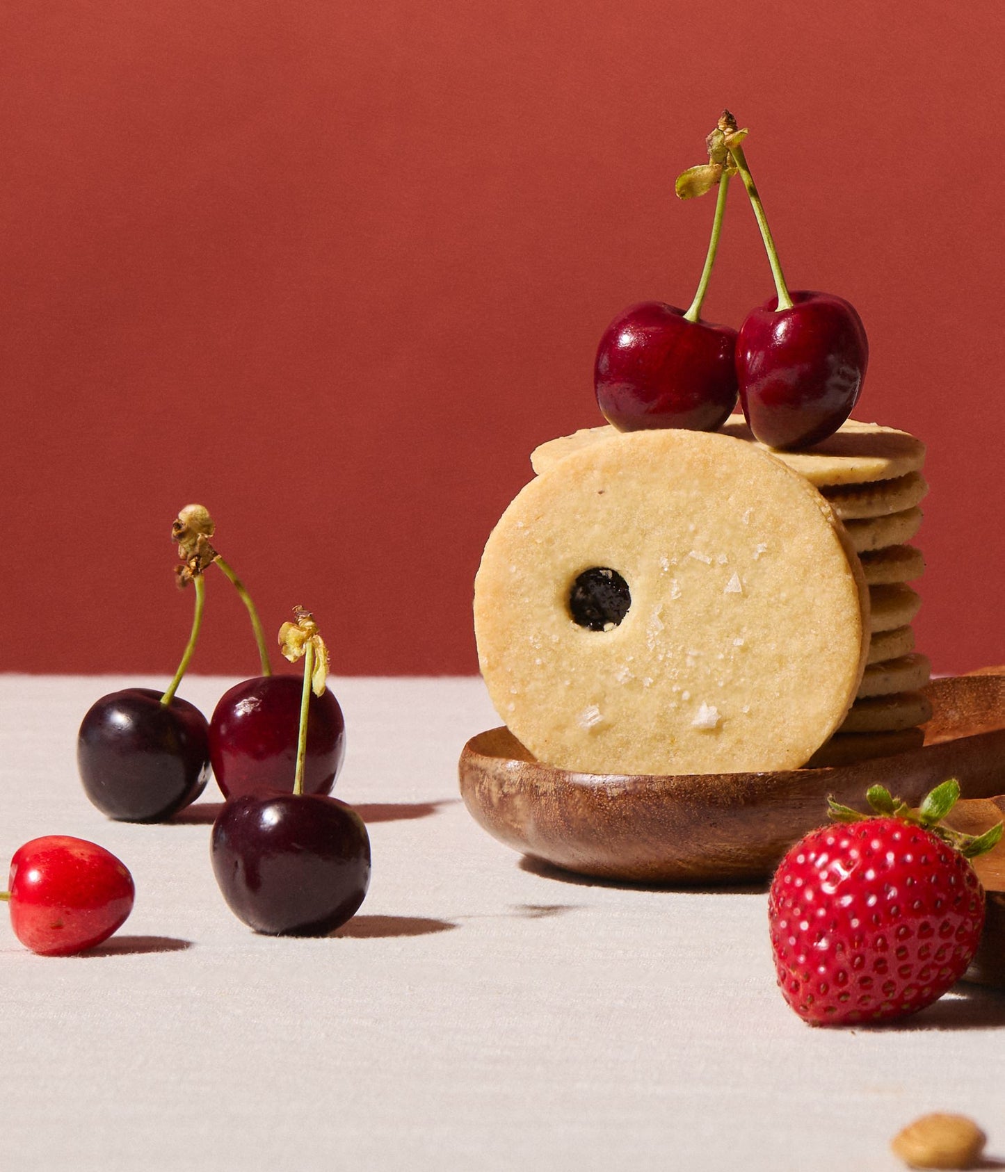 Cookies with cherries and a strawberry on a wooden board against a red background