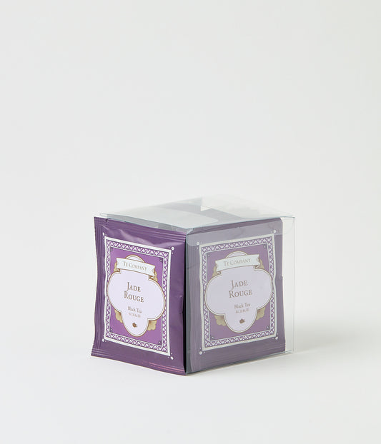 Stack of Te Company Jade Rouge black tea packets packaged in a clear plastic box against a white background.