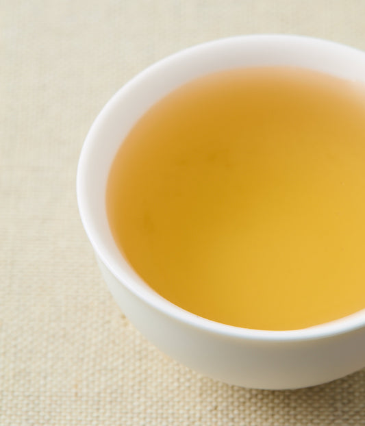 A cup of golden herbal tea in a white bowl.