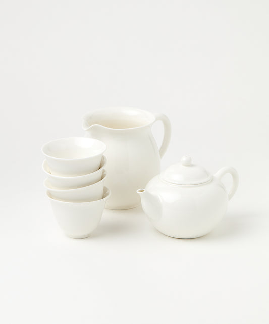 A porcelain brewing set featuring a white teapot, pitcher, and four stacked cups.