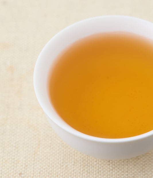 Golden amber liquor of Honeyed Black tea in white ceramic cup
