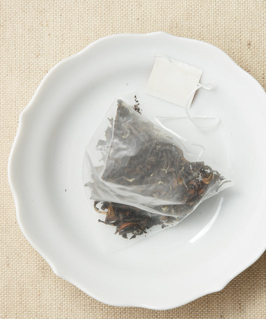 A pyramid-shaped tea sachet filled with dried leaves.