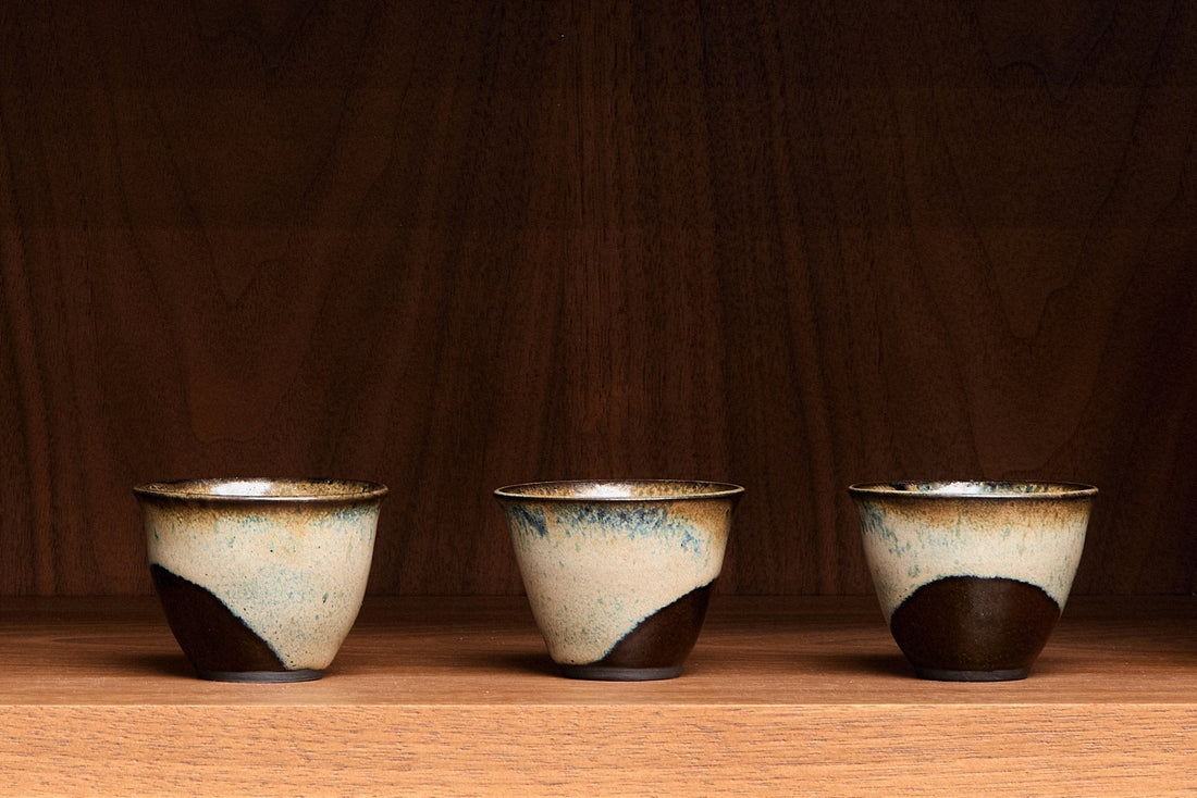 Three ceramic cups with a rustic finish on a wooden surface