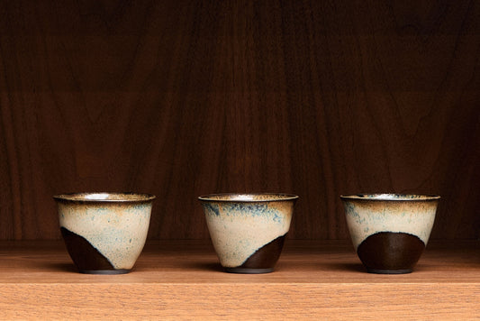 Three ceramic cups with a rustic finish on a wooden surface