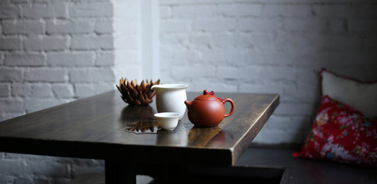 Tea set on wooden table with white brick wall.