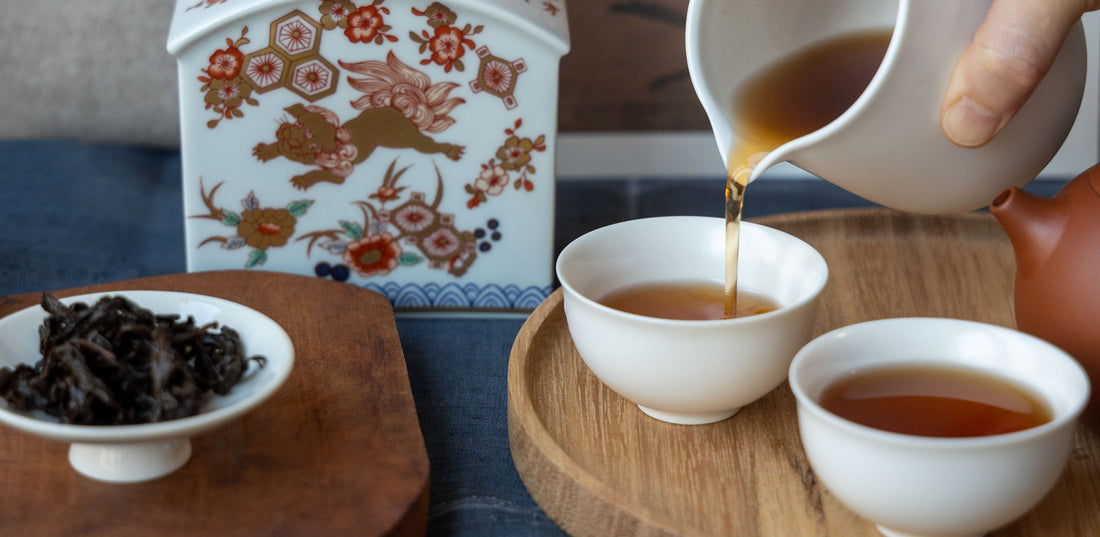 Pouring tea into cups with a decorated container.