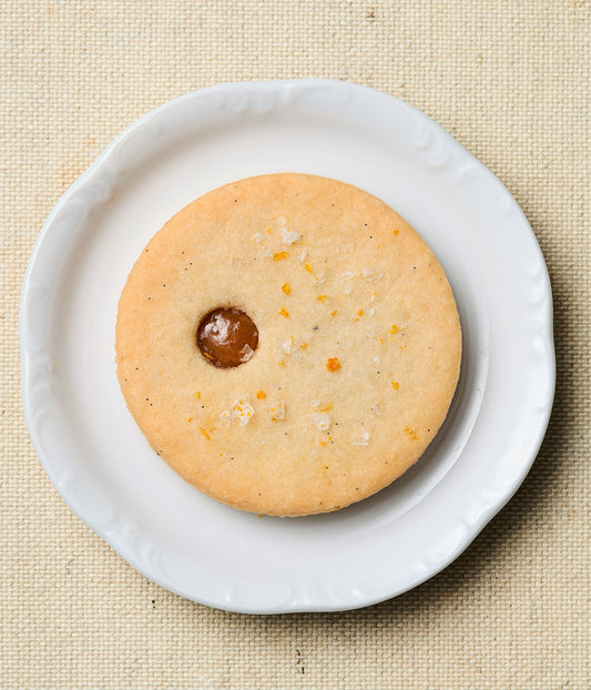 linzer cookie with a calamansi center on a white plate against a beige background