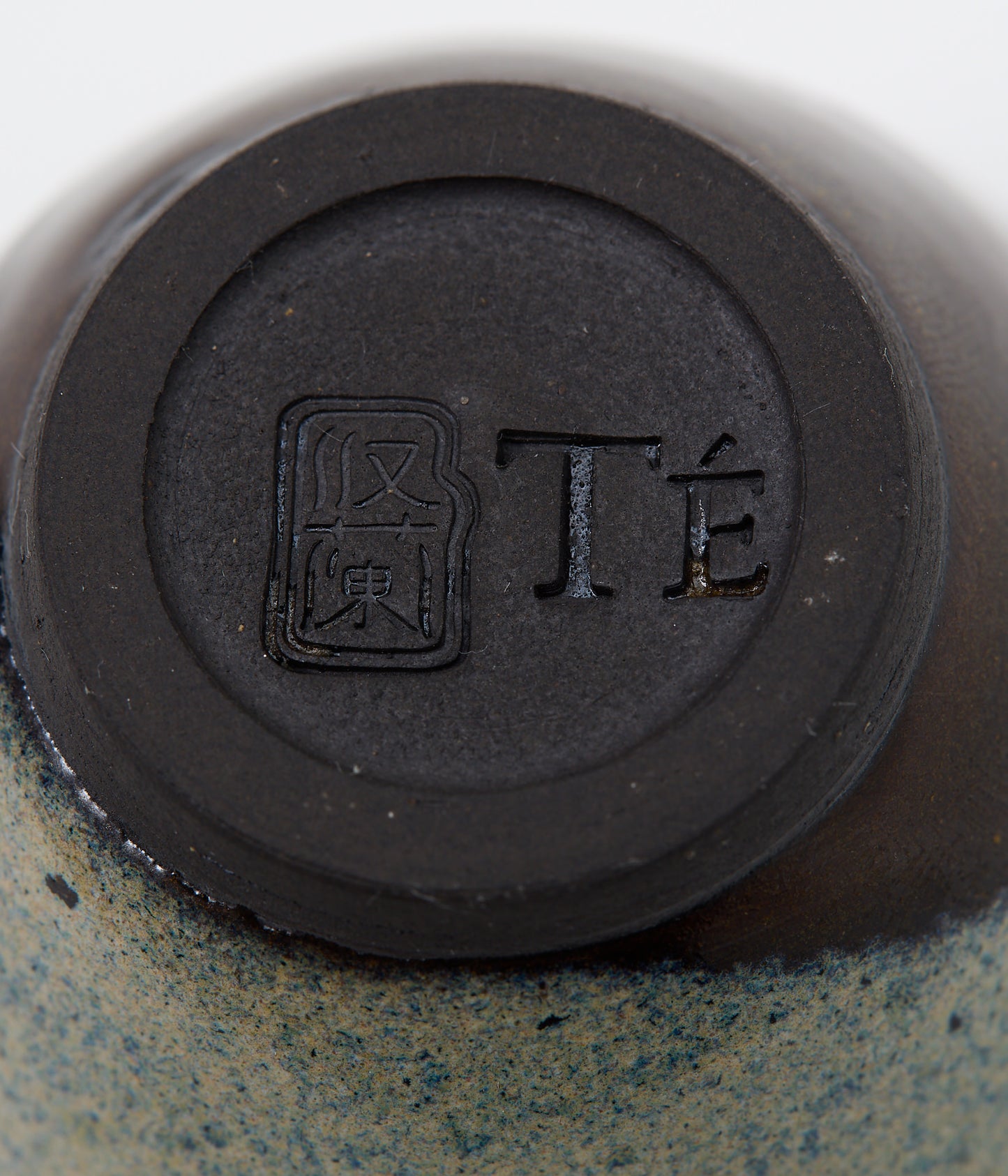 Close-up of a ceramic product with a black circular mark and text on a beige background