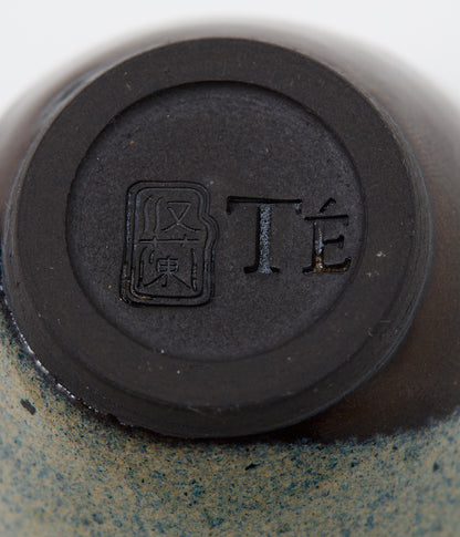 Close-up of a ceramic product with a black circular mark and text on a beige background