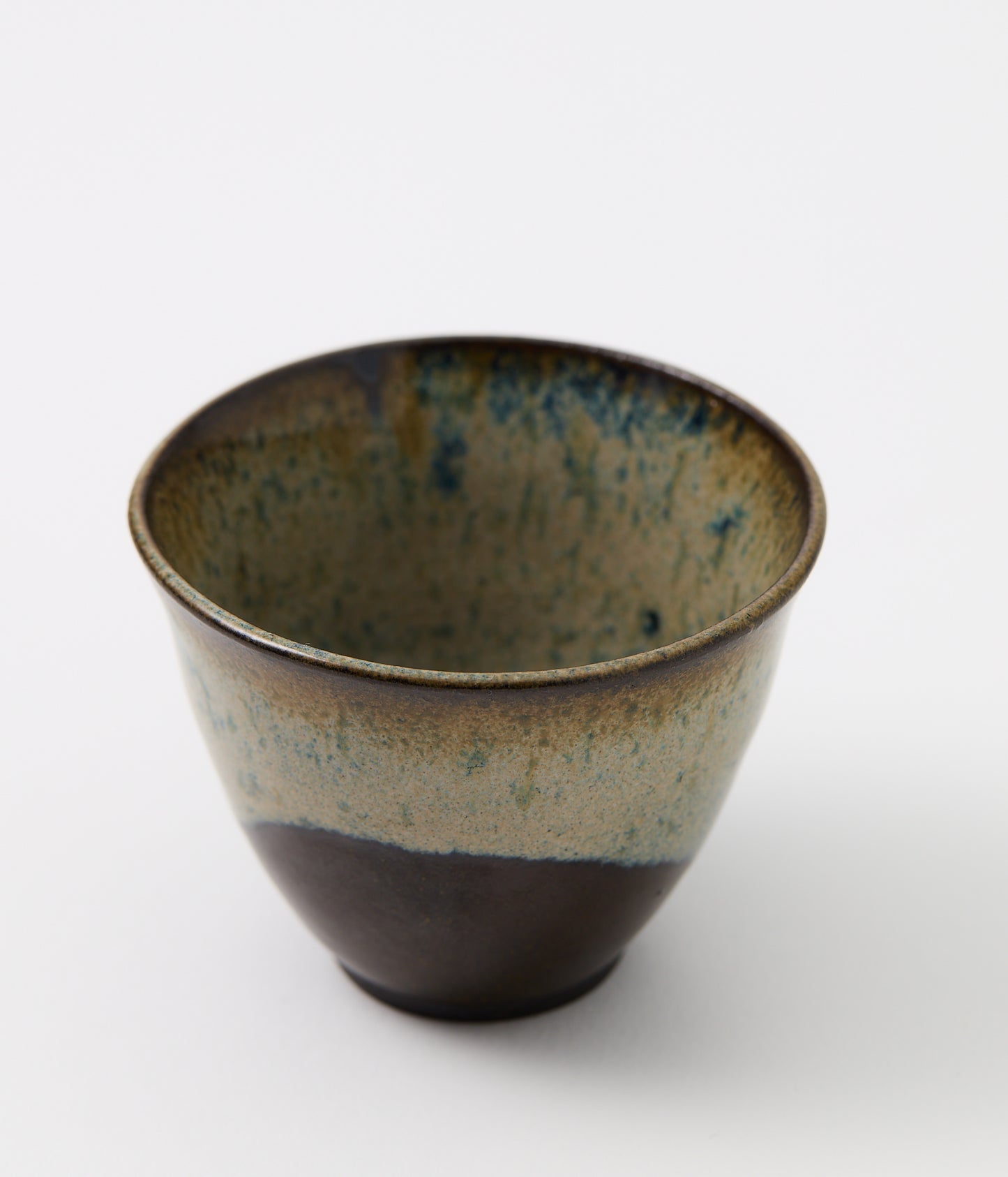 Ceramic cup with speckled glaze on a white background