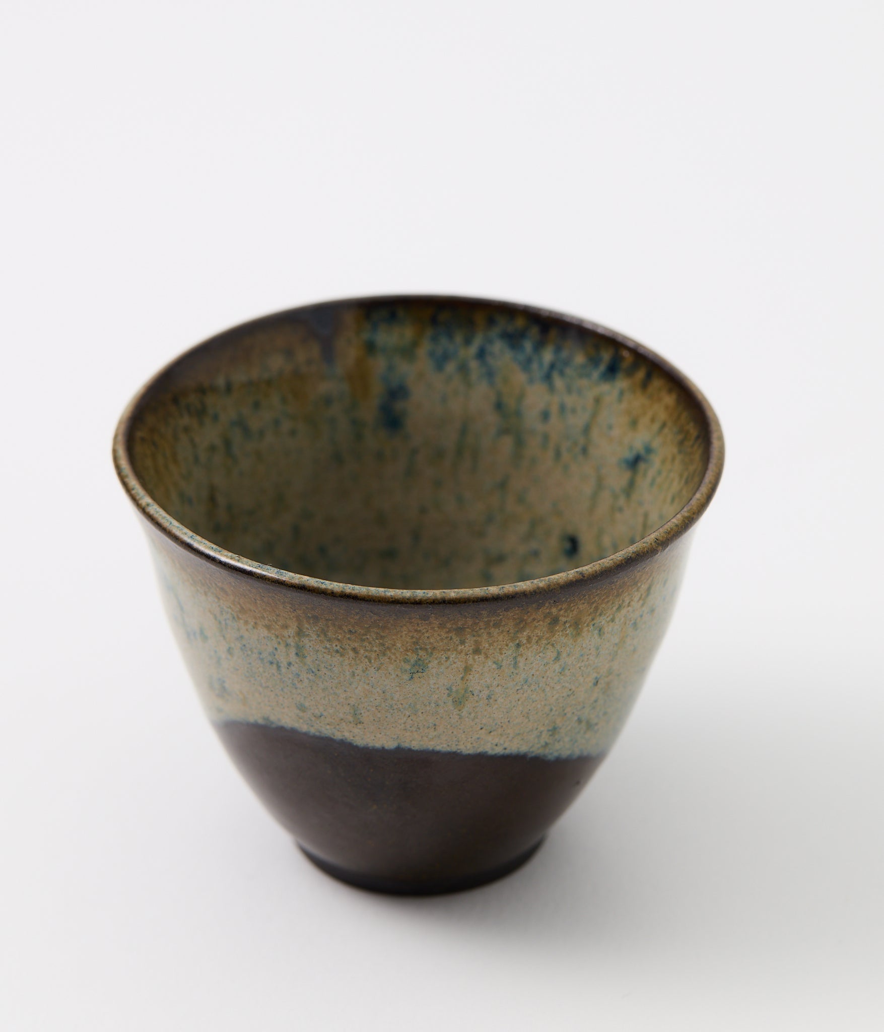 Ceramic cup with speckled glaze on a white background