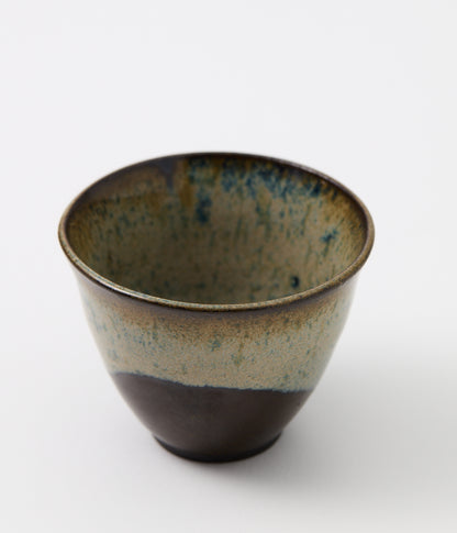 Ceramic cup with speckled glaze on a white background