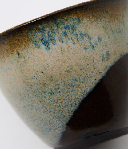 Close-up of a ceramic bowl with speckled glaze on a white background