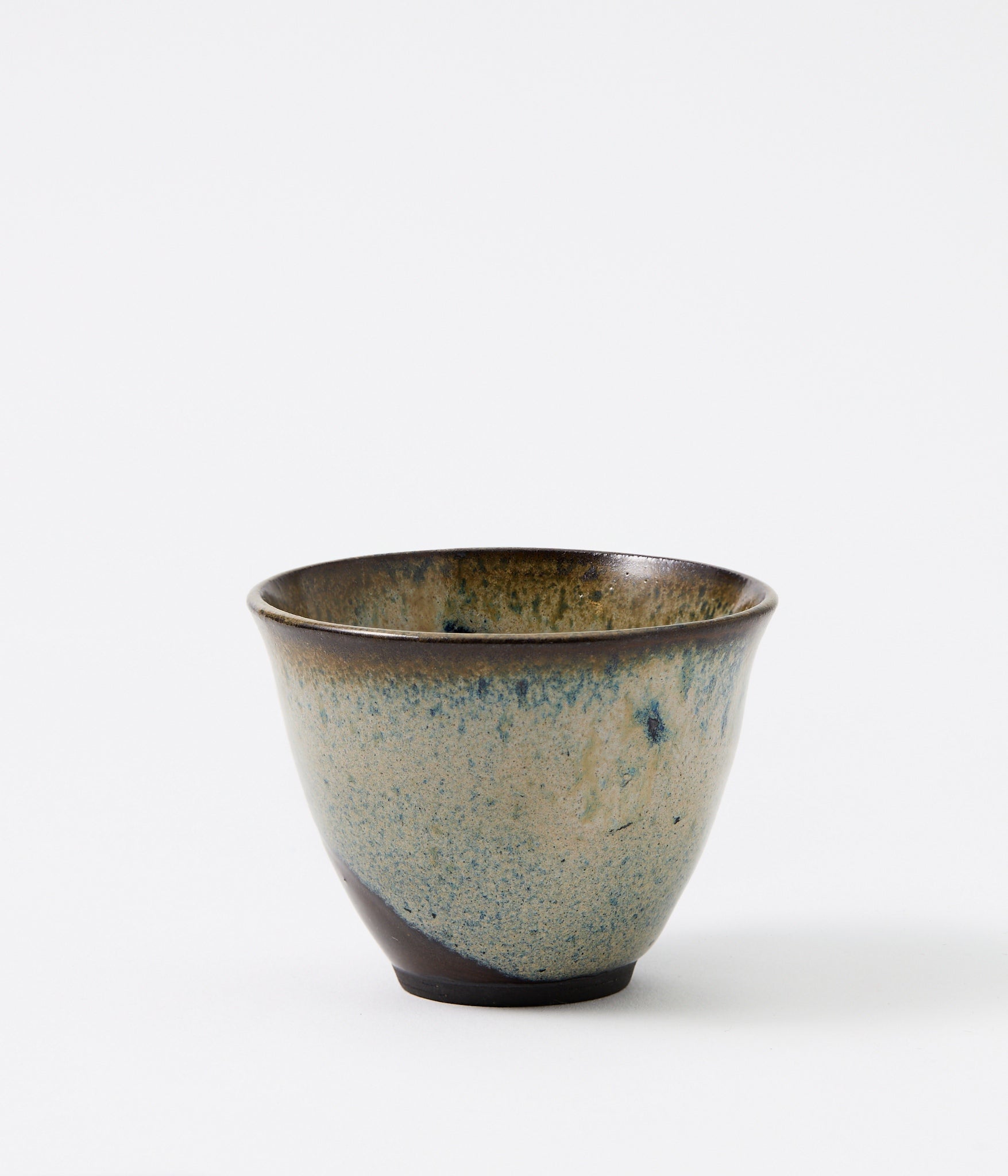 Ceramic cup with speckled glaze on a white background