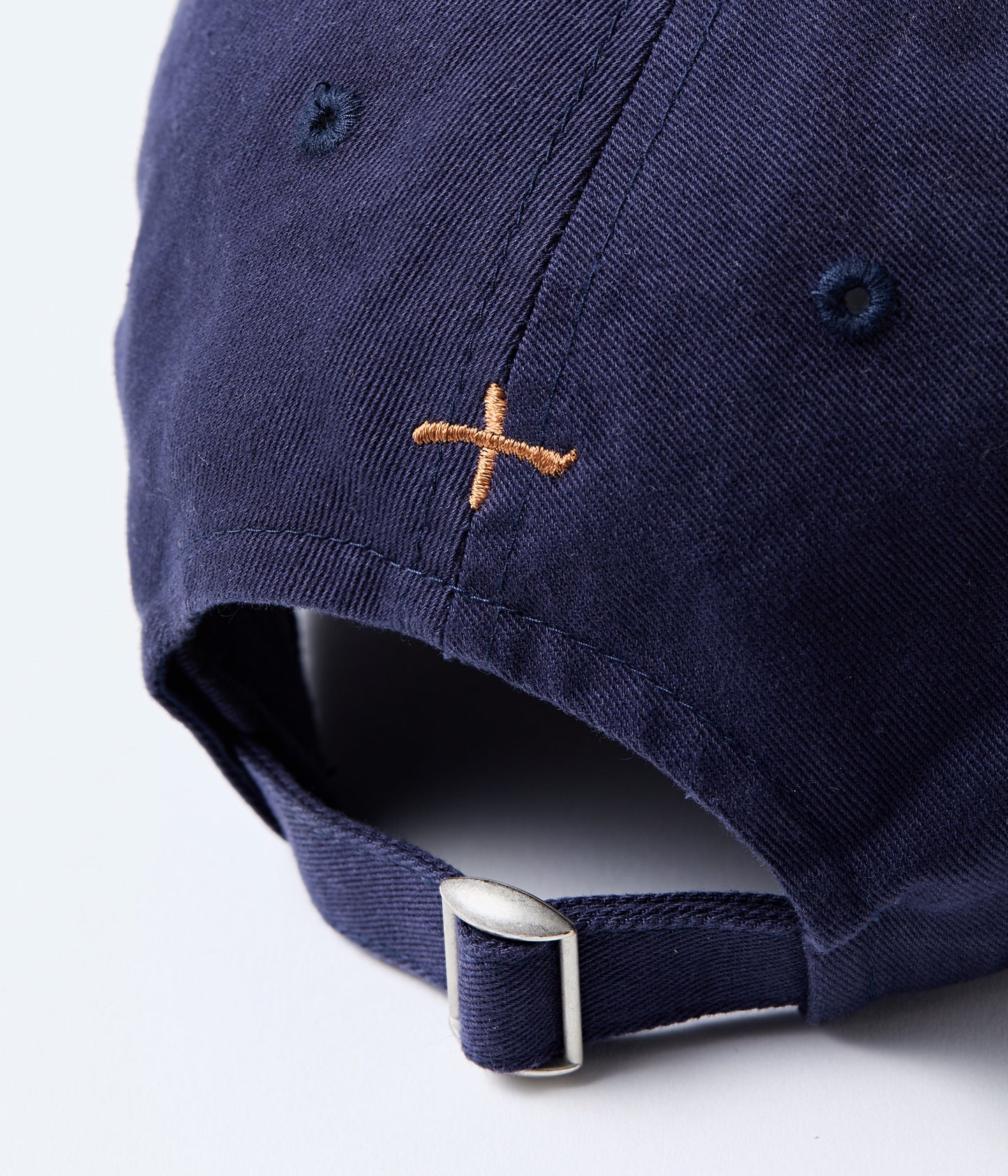 Navy blue cap with a brown embroidered logo on the back, on a white background