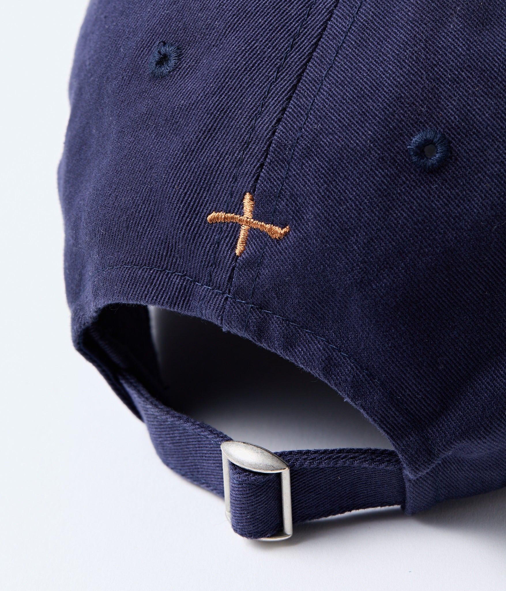 Navy blue cap with a brown embroidered logo on the back, on a white background