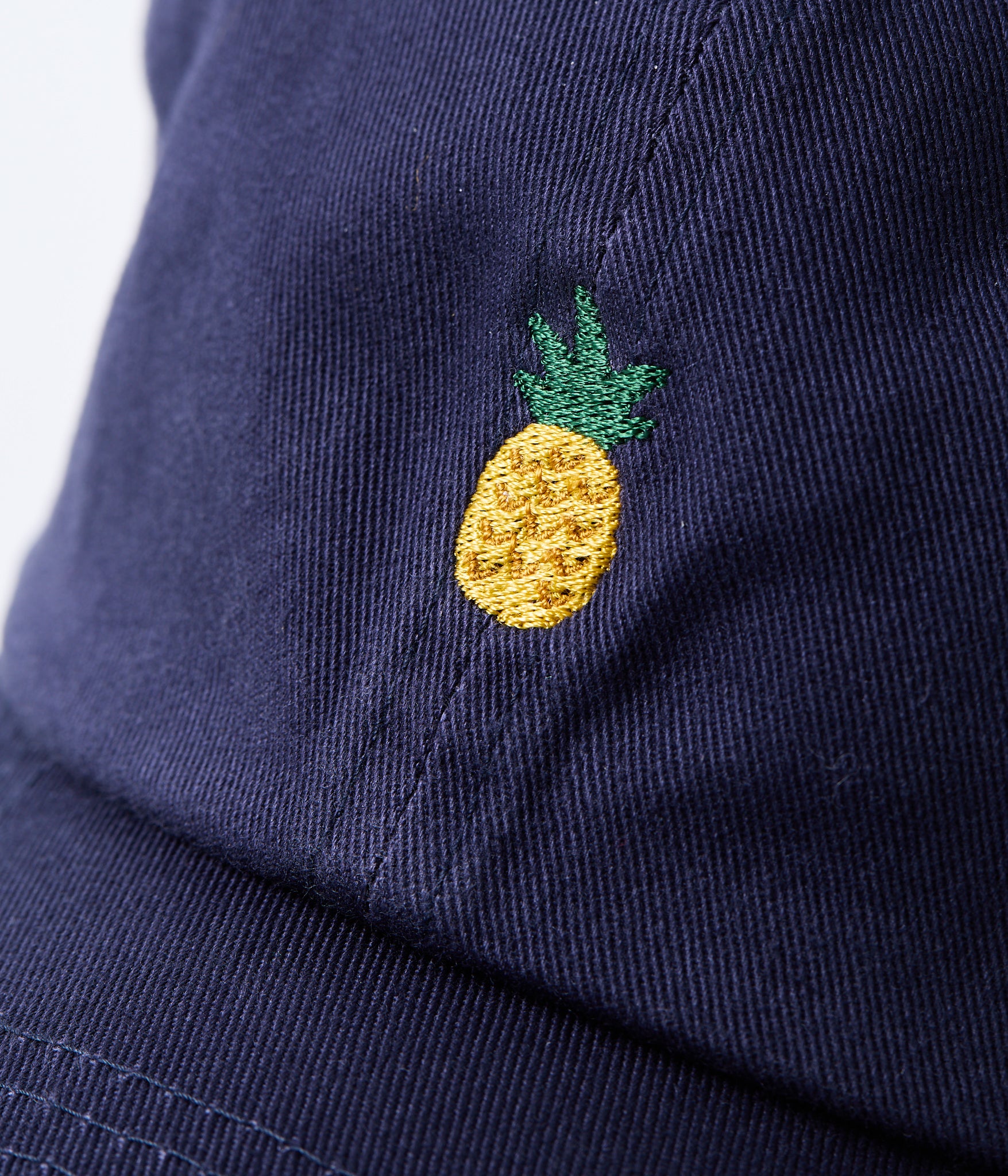 Navy blue cap with a embroidered yellow pineapple on a white background