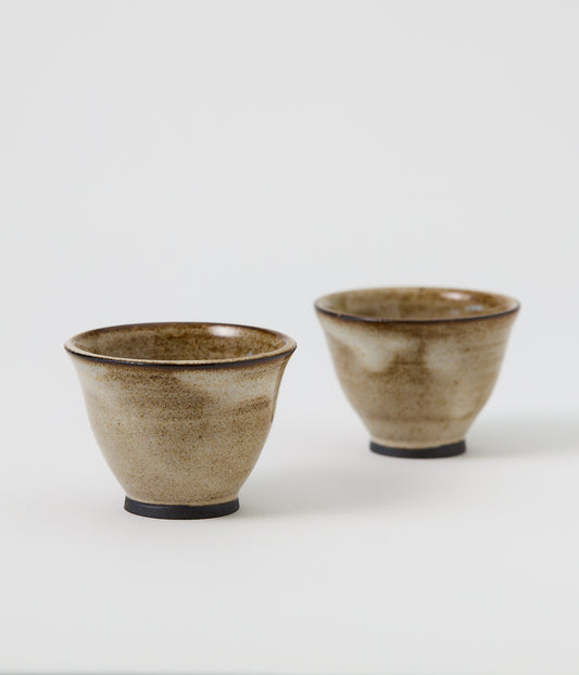 Two ceramic cups with a brown speckled glaze on a white background