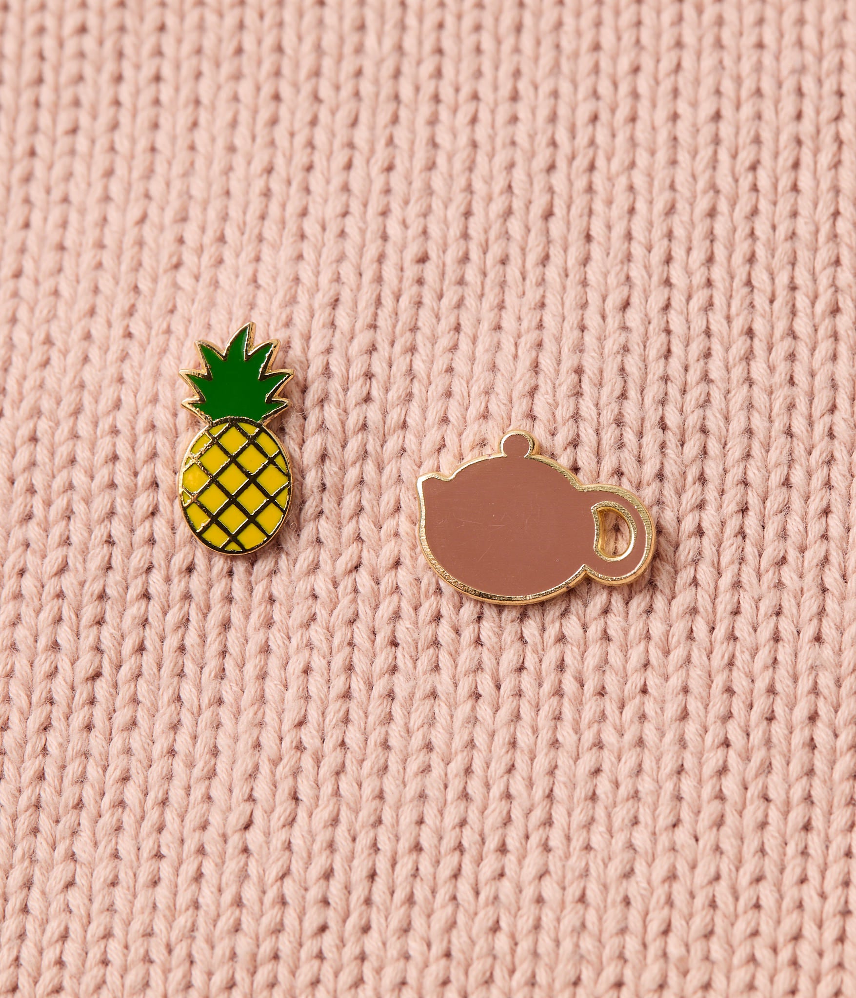 Pineapple and teacup pins on a pink knitted shirt
