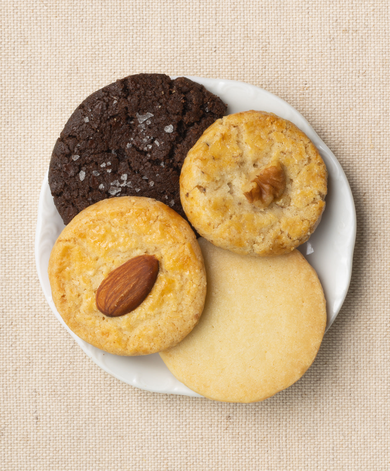 Assorted Button Cookies, including almond, walnut, shortbread, and chocolate, on a white plate.