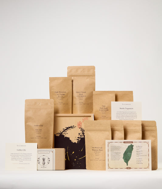 Big grouping of tea bags and tea labels with a box of treats and a decorate box.
