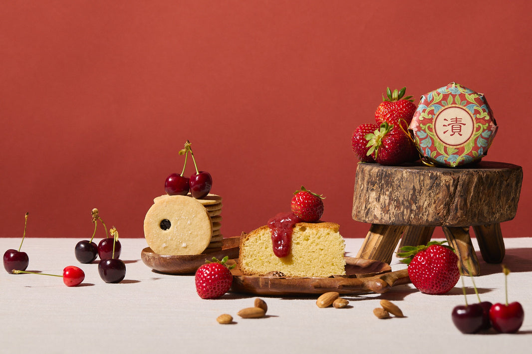 Assorted desserts with strawberries and cherries on a wooden stand against a red background
