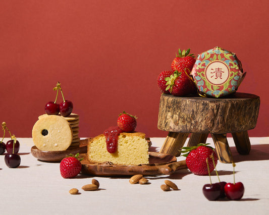 Assorted desserts with strawberries and cherries on a wooden stand against a red background