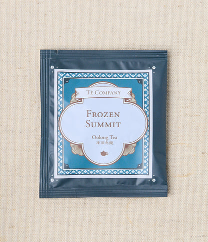 Single packet of Te Company Frozen Summit oolong tea on a beige textured background.