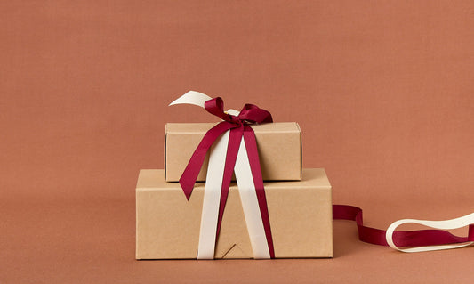 Two brown gift boxes with red and white ribbons on a brown background