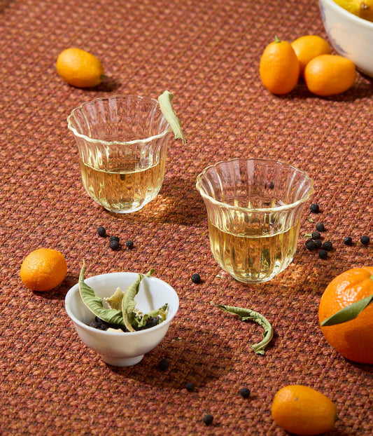Two glasses of herbal tea with kumquats and spices.