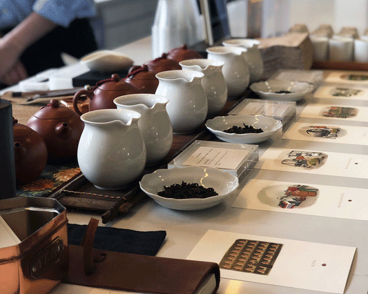 Tea tasting setup with teapots, pitchers, and loose leaf tea samples.