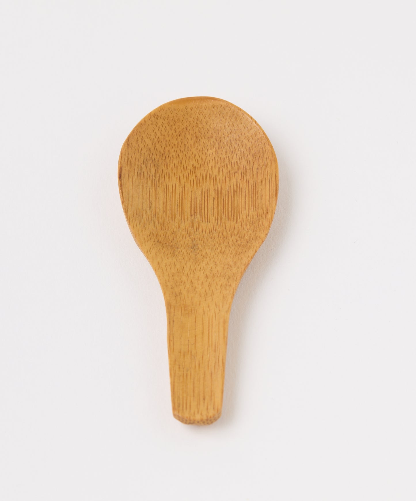 Top view of a bamboo tea spoon with a rounded head and natural wood grain.