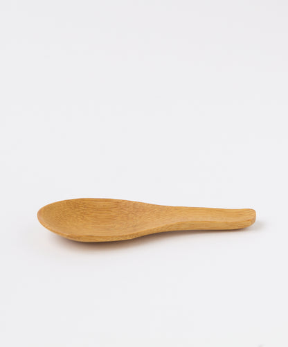 Side profile of a bamboo tea spoon highlighting its curved design.