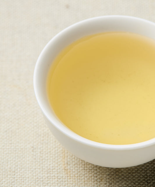 White cup filled with yellow liquid on a textured beige surface