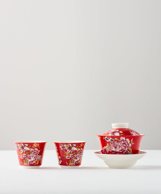 Two red cups and a gaiwan set with floral designs.