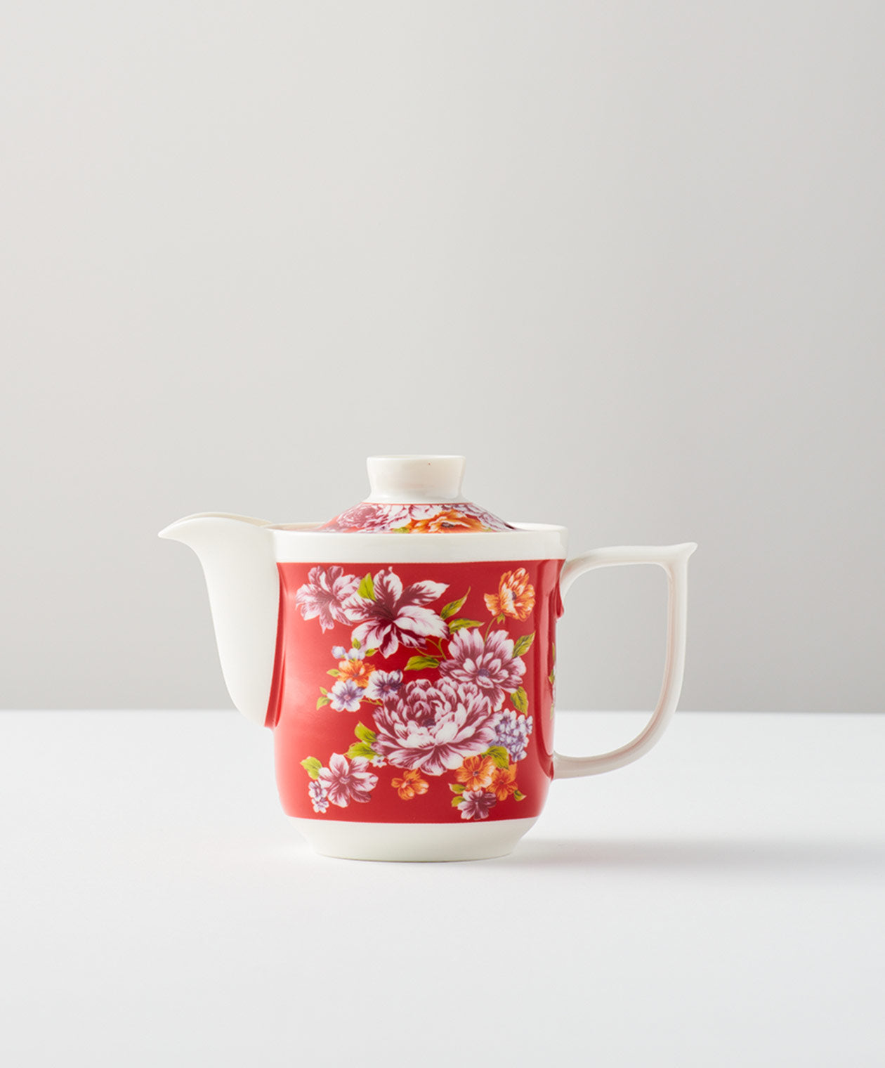 Red floral teapot on a white surface with lid