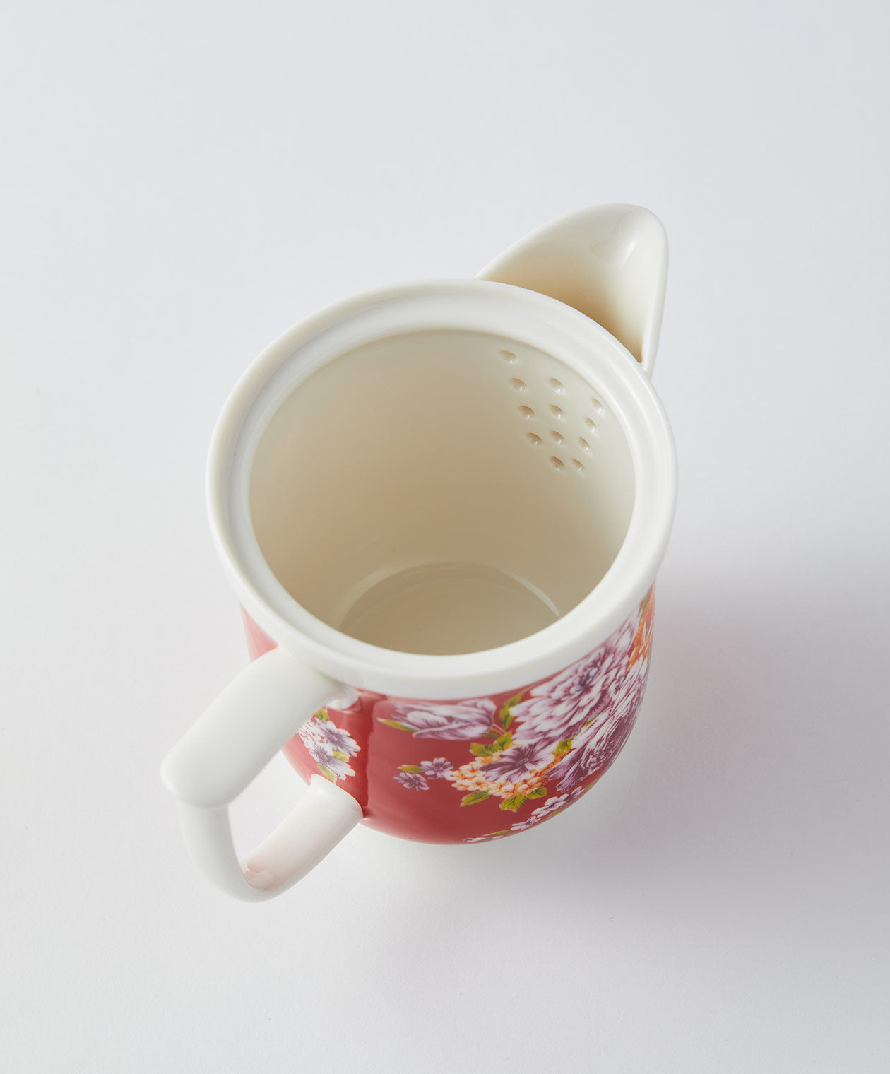 Interior view of a red floral teapot showing strainer holes.