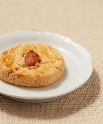 Close-up of an almond-topped Button Cookie on a white plate.