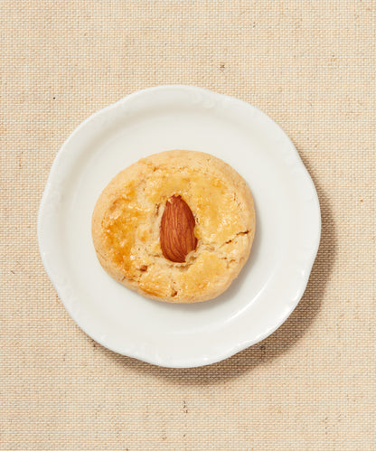 Single almond-topped Button Cookie on a white plate